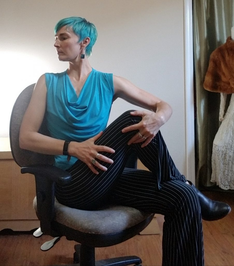 Woman seated in an office chair, twisting into a seated spinal twist